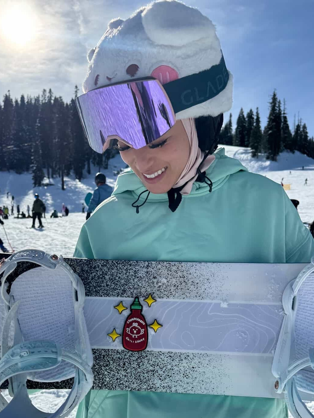 Person holding a snowboard with a design on a snowy landscape